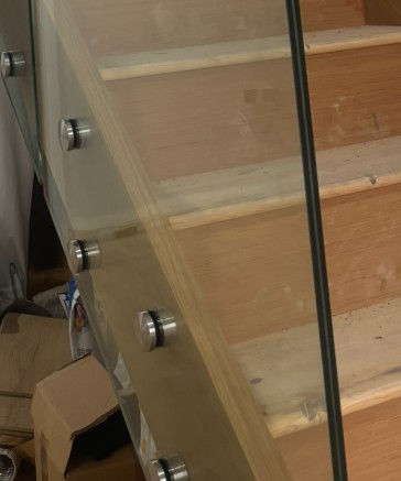 Close-up of stainless steel standoff button fixing on frameless glass staircase panel