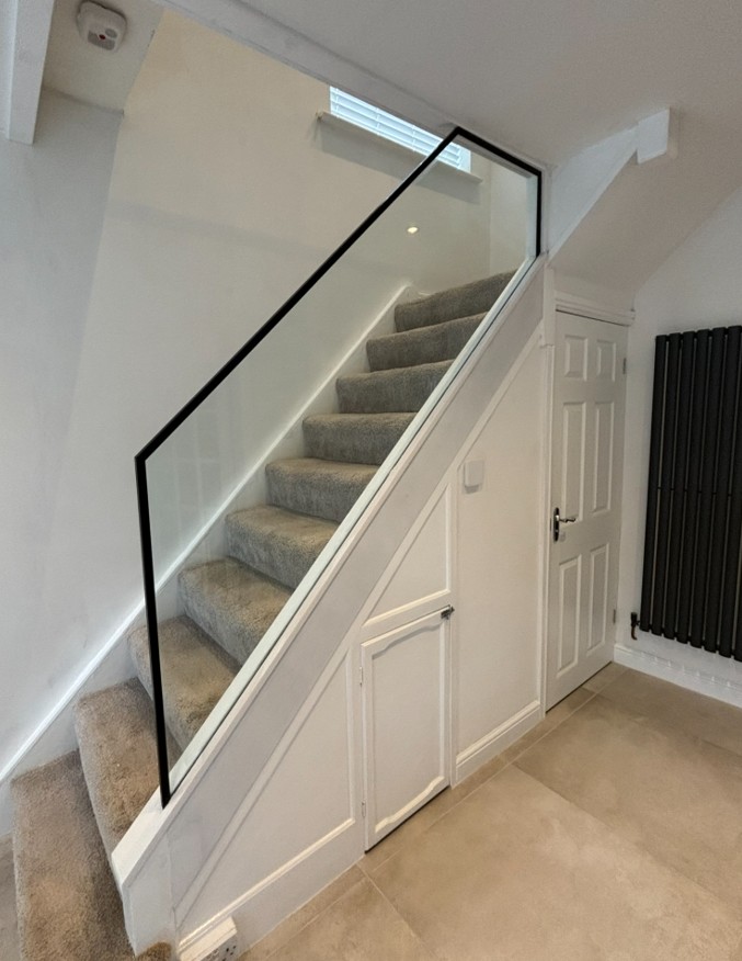 Close-up of stringer cladding concealing glass fixings on frameless staircase renovation