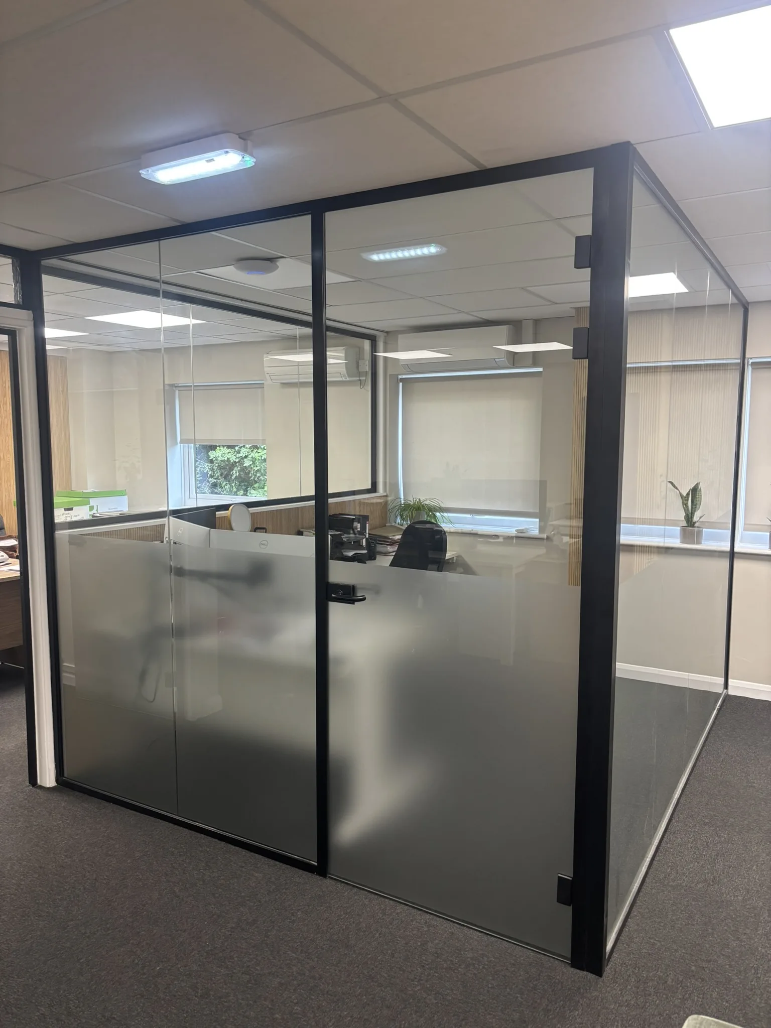 Completed black framed glass office partition installation with full-height doors and frosted glazing