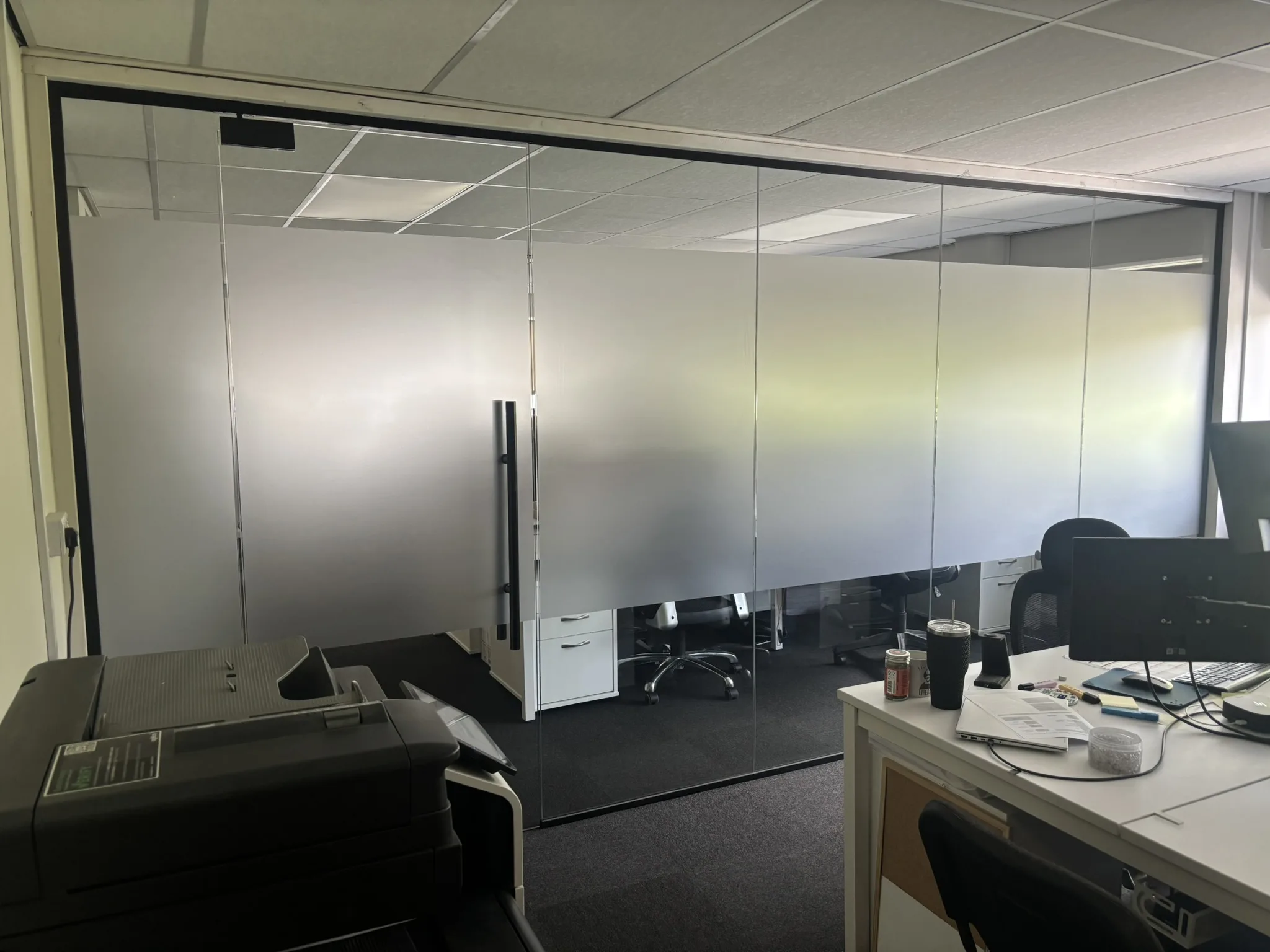 Full-height glass office partition with black aluminium frame and matching glazed door