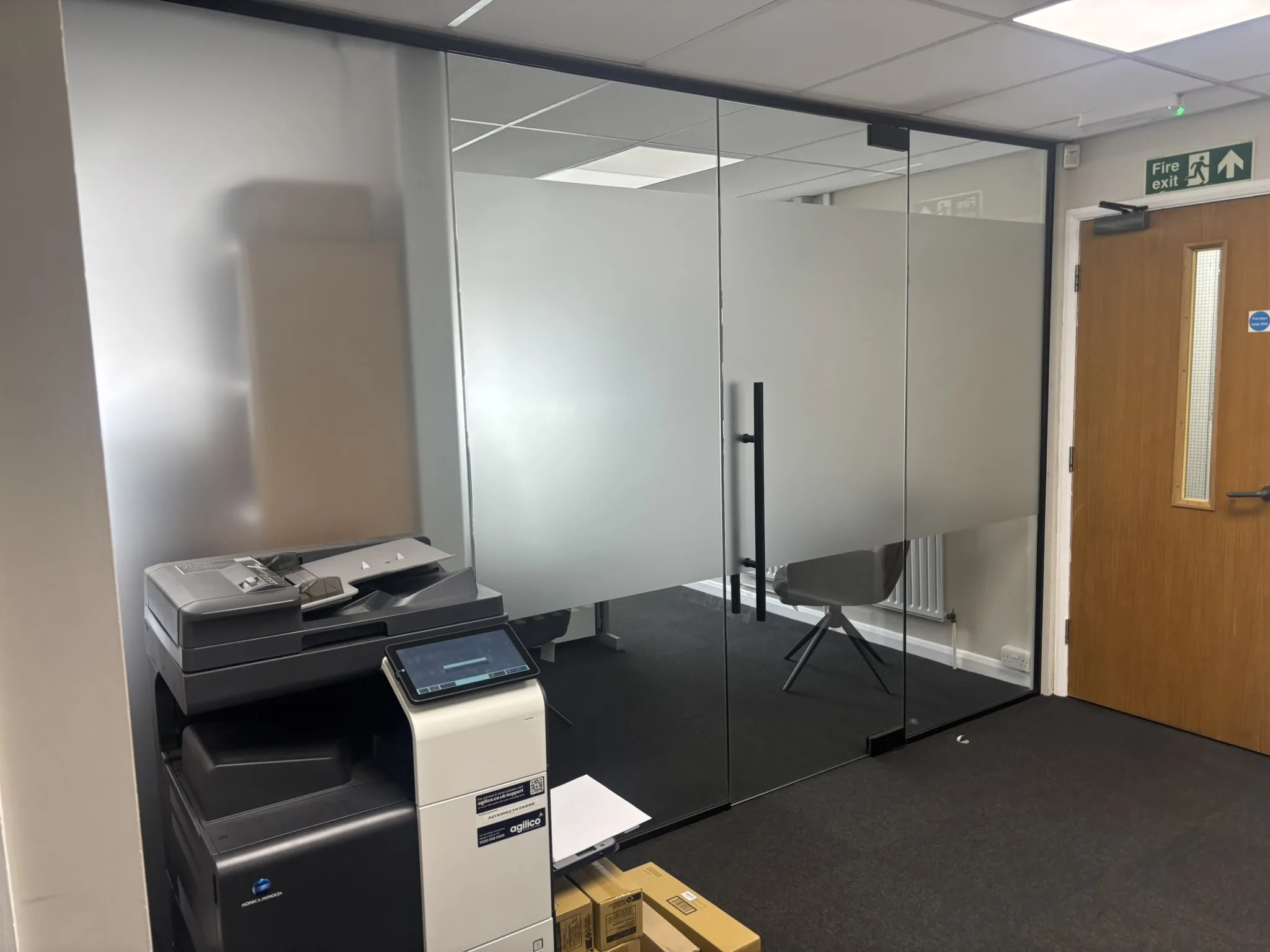 Black framed glass partition system dividing a large office into three separate workspaces