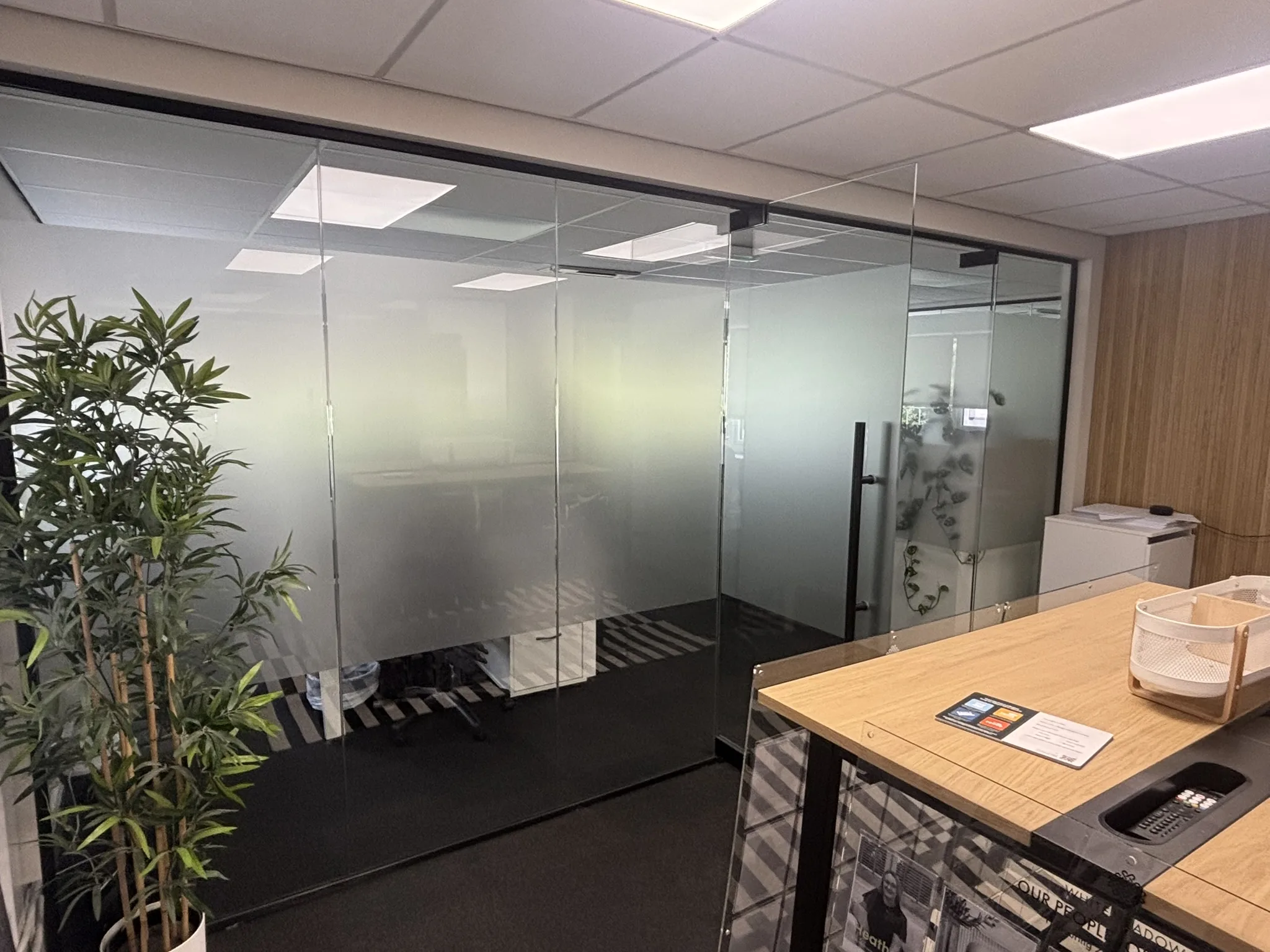 Contemporary office interior featuring black framed glass partitions and privacy frosting