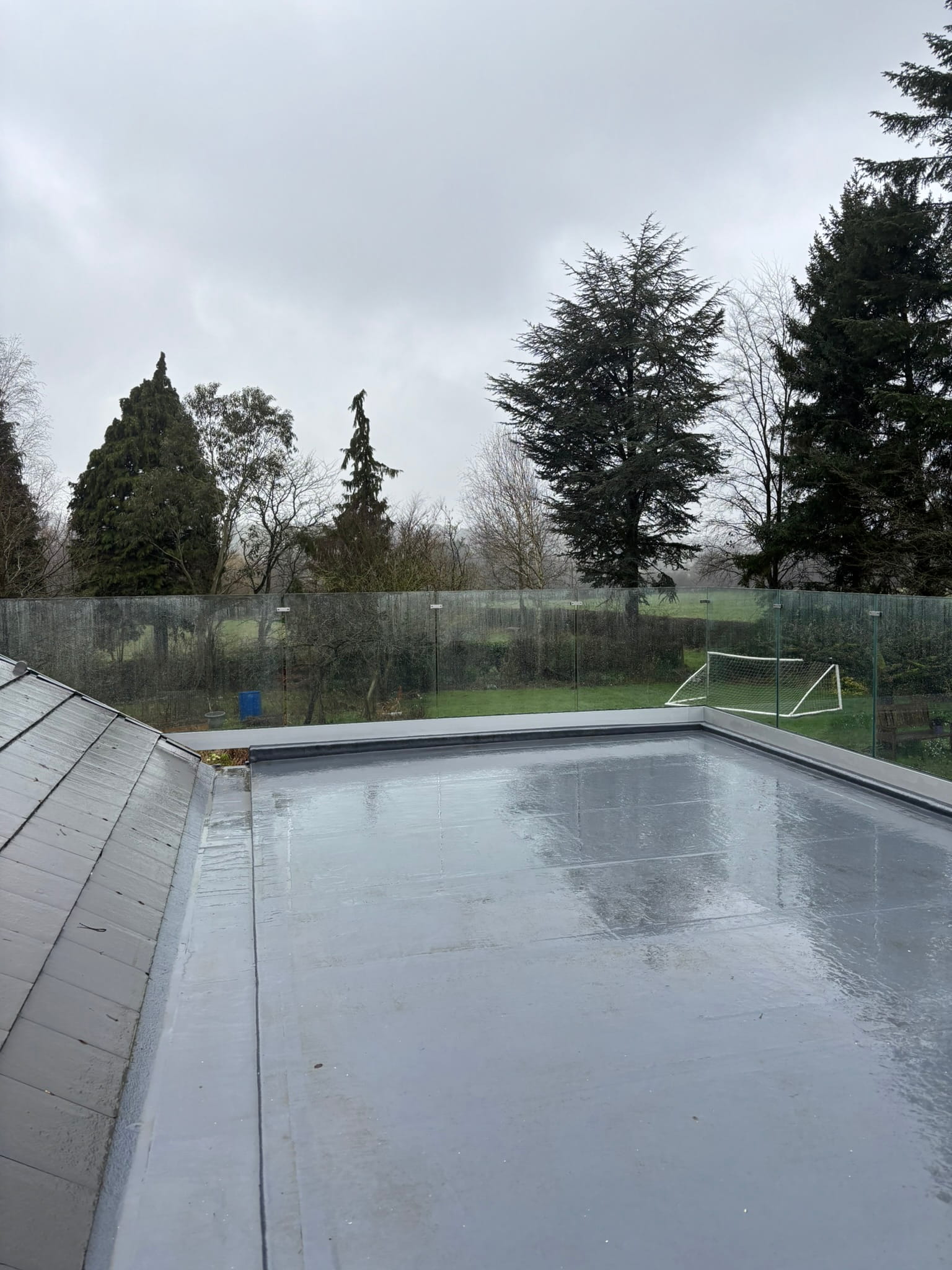 Frameless channel glass balustrade on flat roof terrace in Doncaster, viewed from above looking over garden