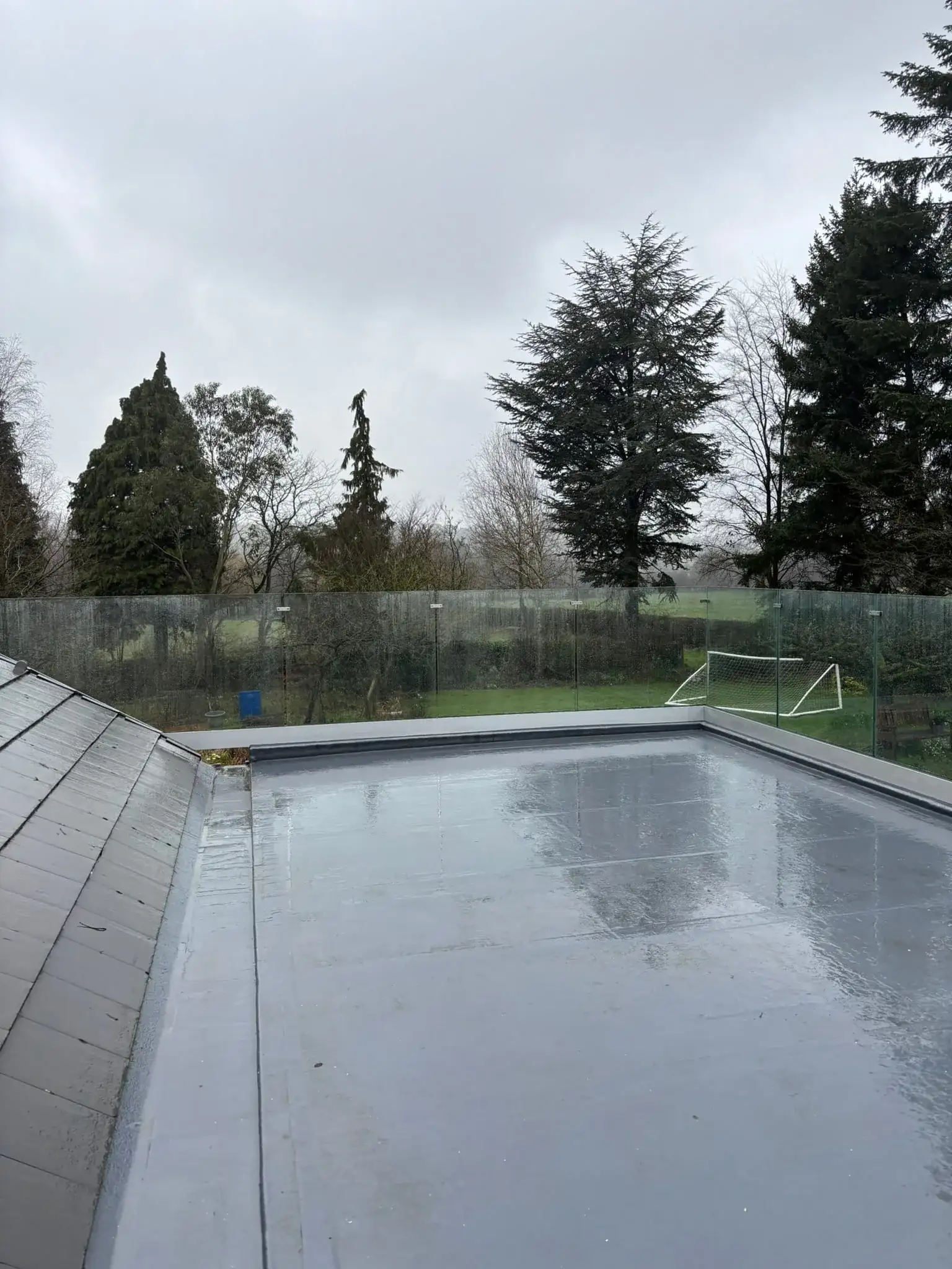 Frameless glass balustrade on flat roof above bifold sliding doors, viewed from garden in Doncaster