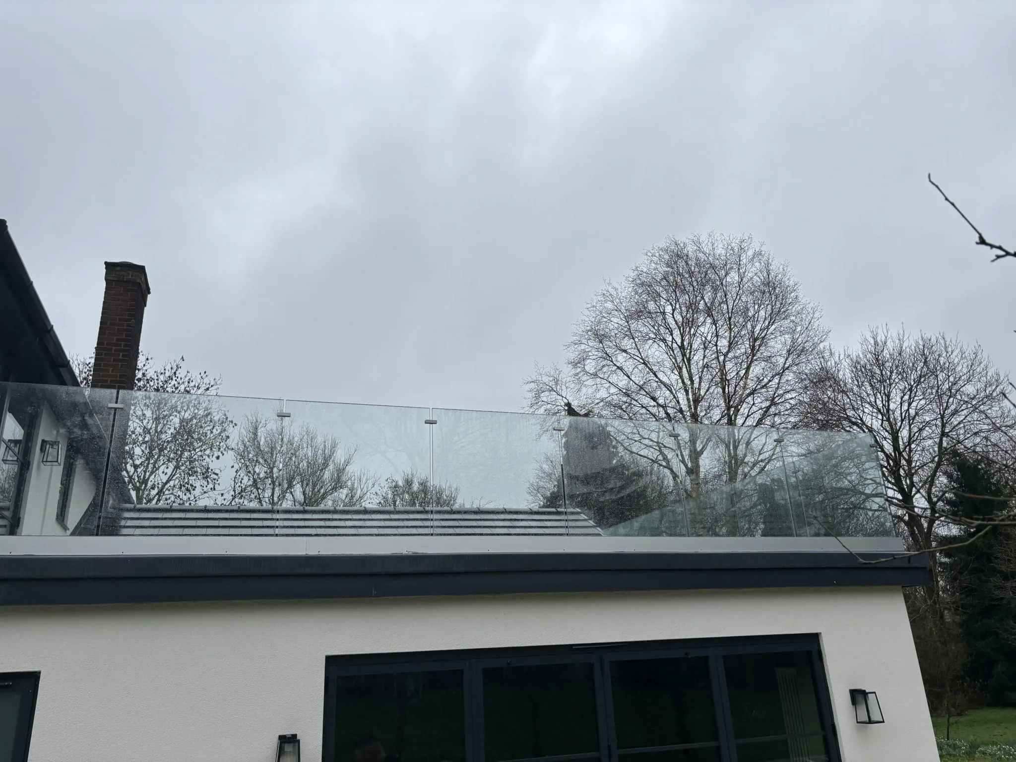 Full exterior of Doncaster property with frameless glass balustrade above bifold doors