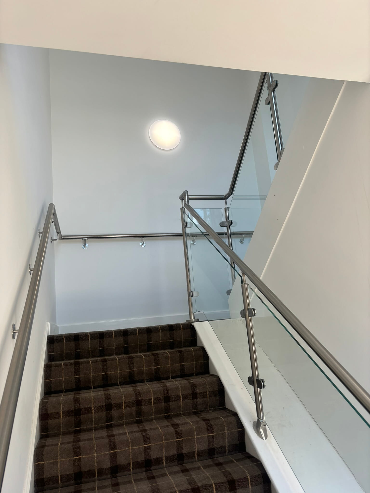 Looking up HMO staircase in Rotherham showing stainless post and glass balustrade on both flights