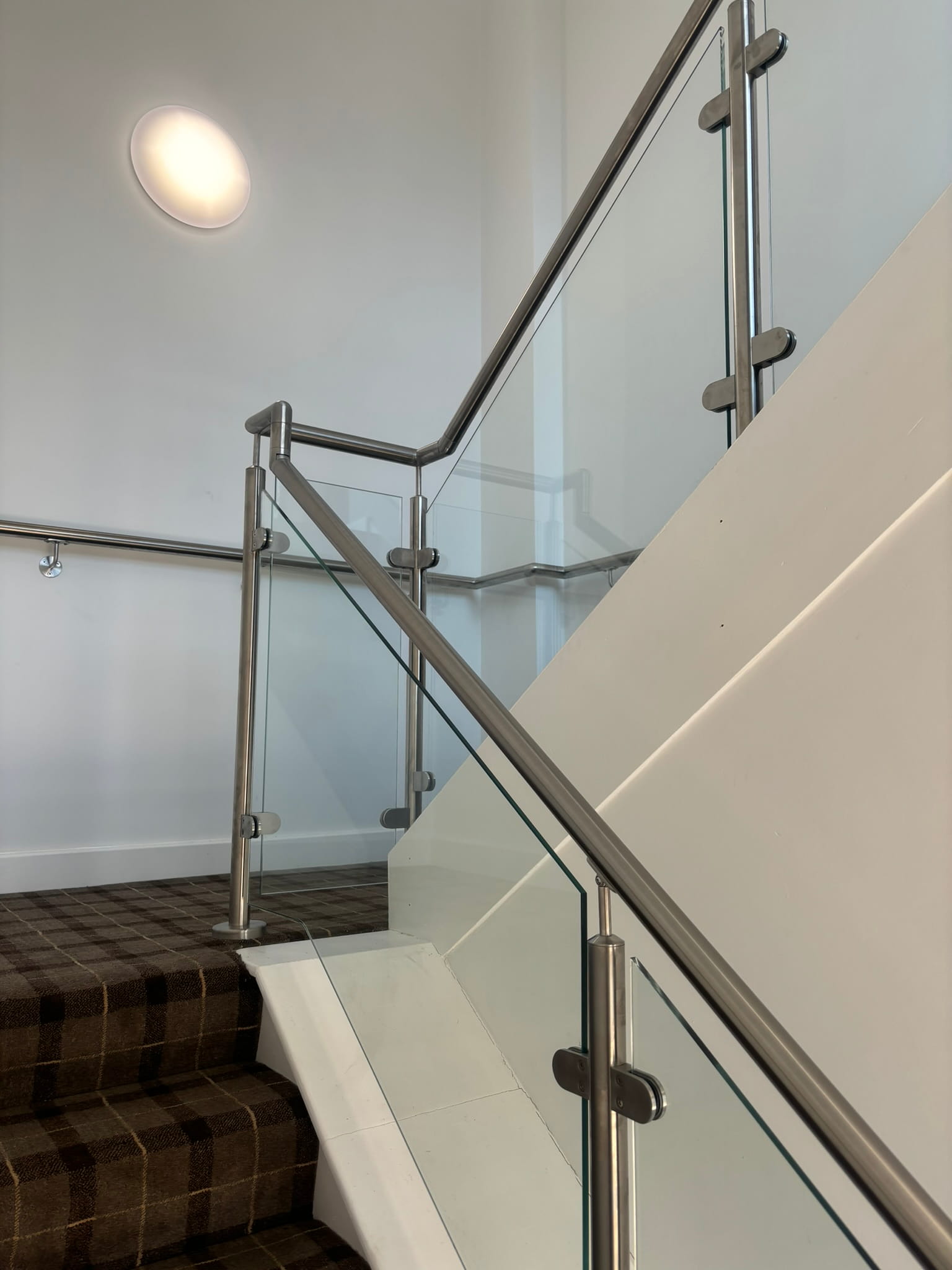 Corner detail of stainless post and glass panel balustrade at staircase turn in Rotherham HMO
