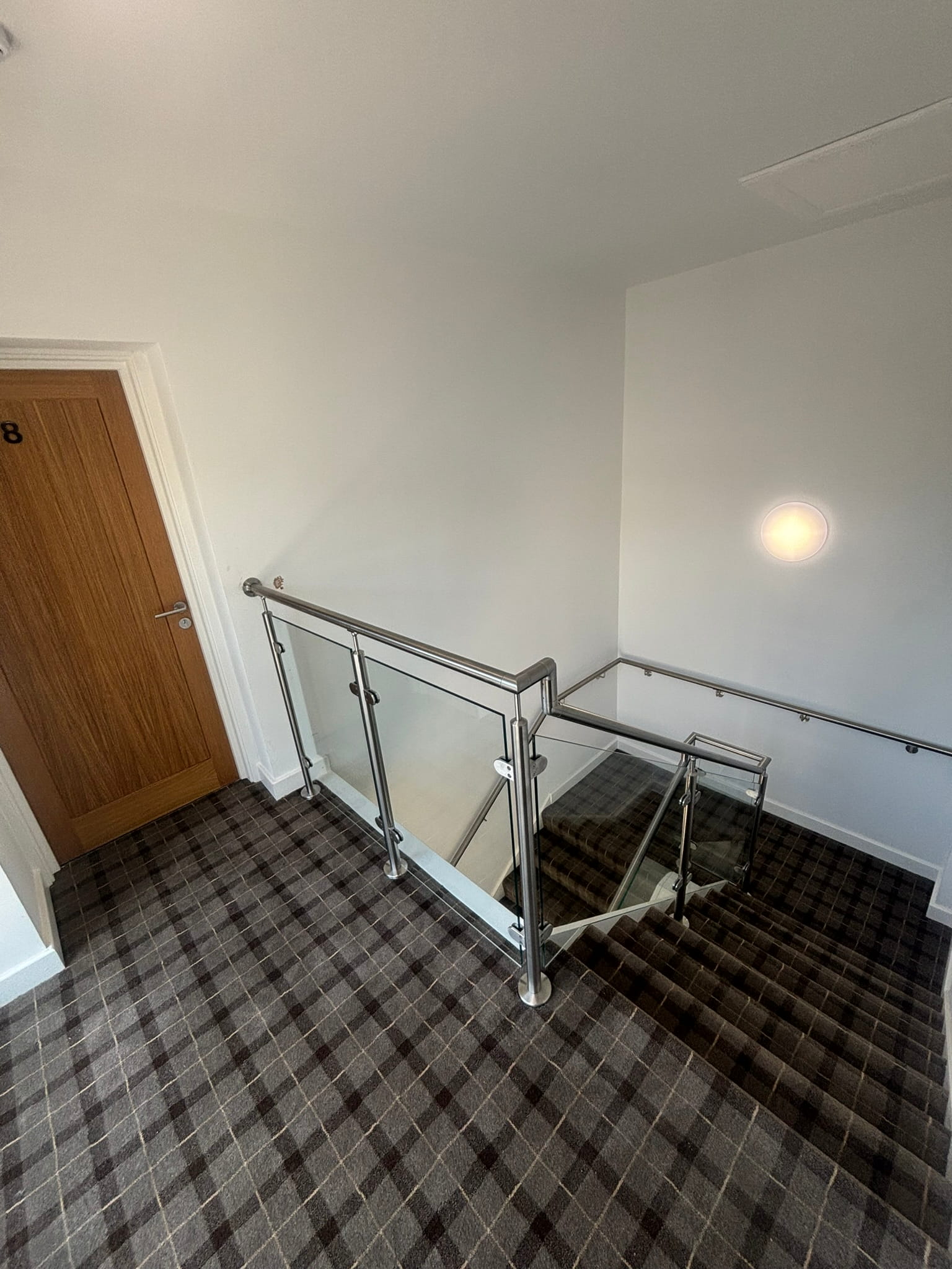 Stainless post and glass balustrade at landing level beside numbered room door in Rotherham HMO