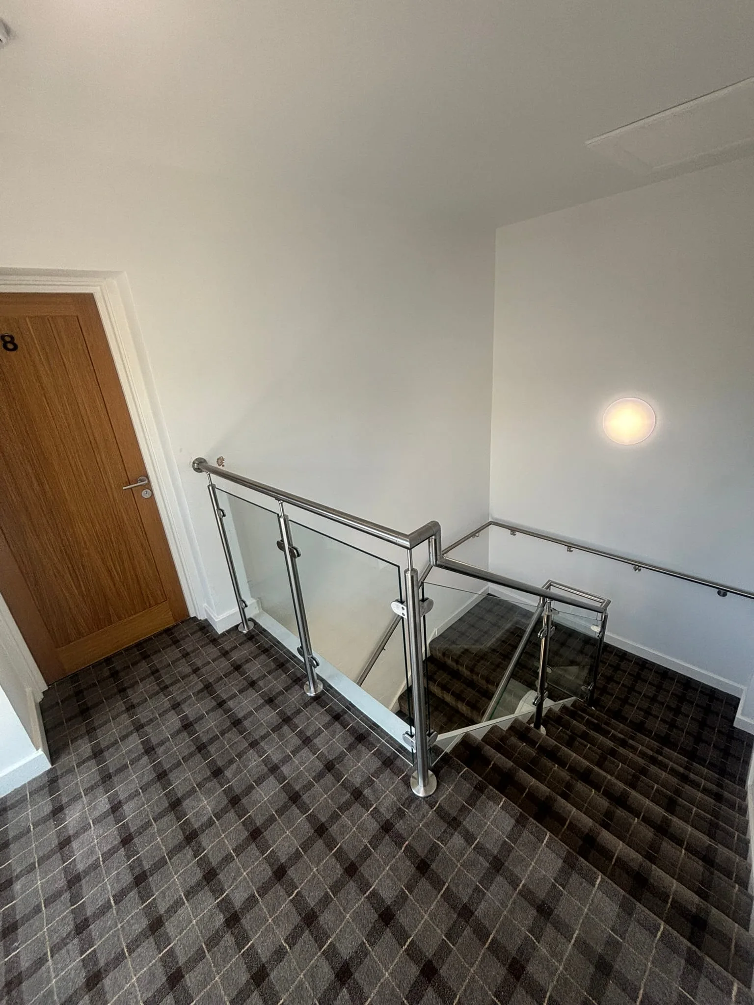 Detail of stainless handrail junction and glass panel balustrade at staircase turn in Rotherham HMO