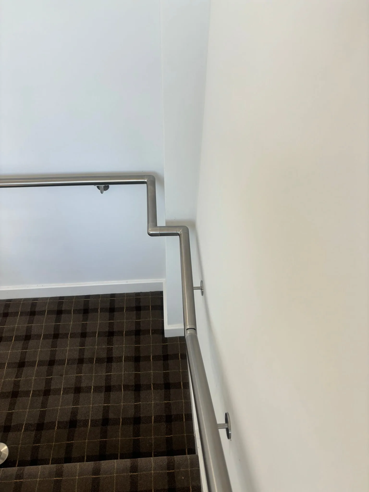 Brushed stainless steel wall-mounted handrail on HMO staircase in Rotherham beside glass balustrade