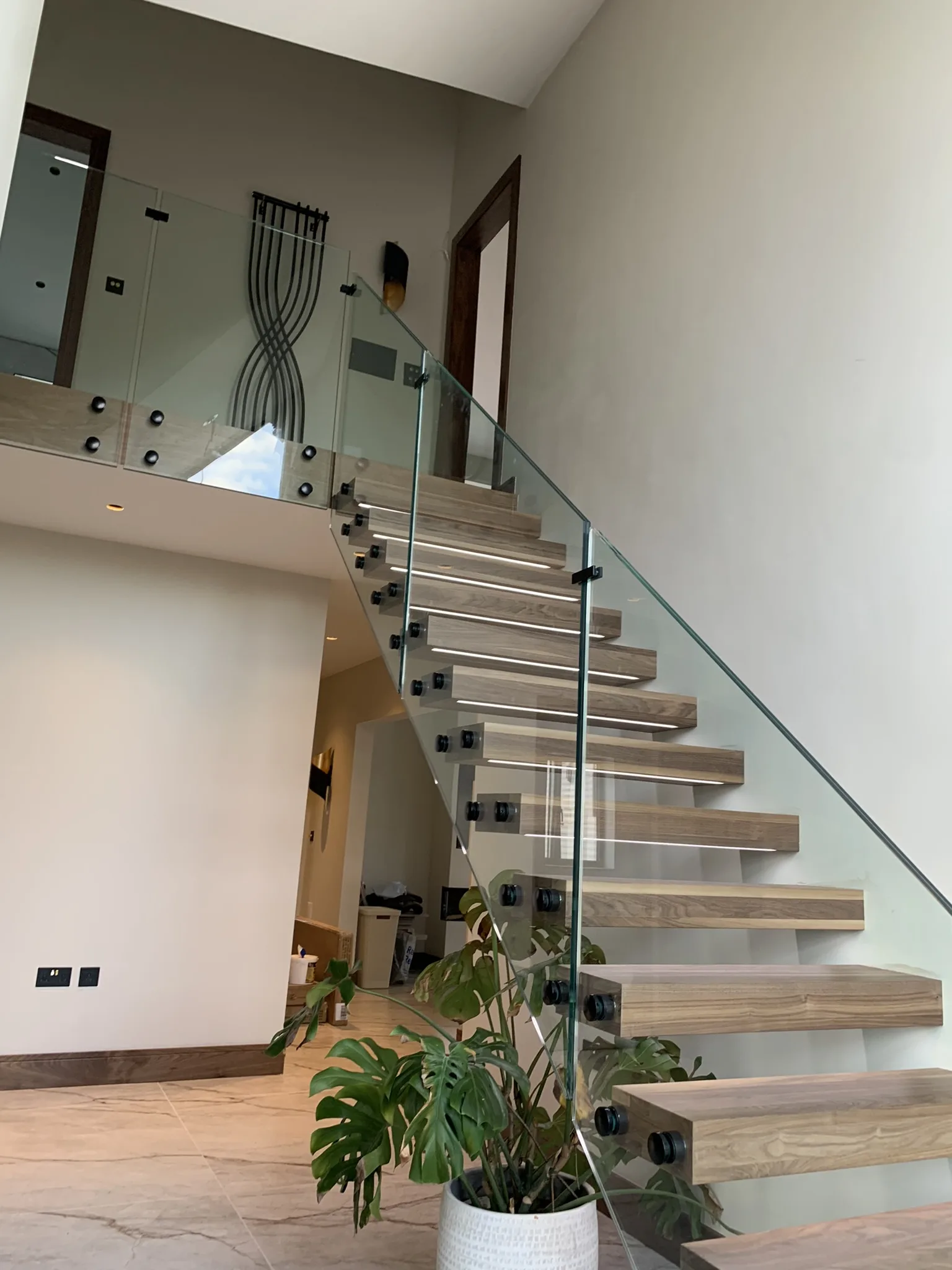 Frameless walnut floating staircase with glass balustrade in Lincoln