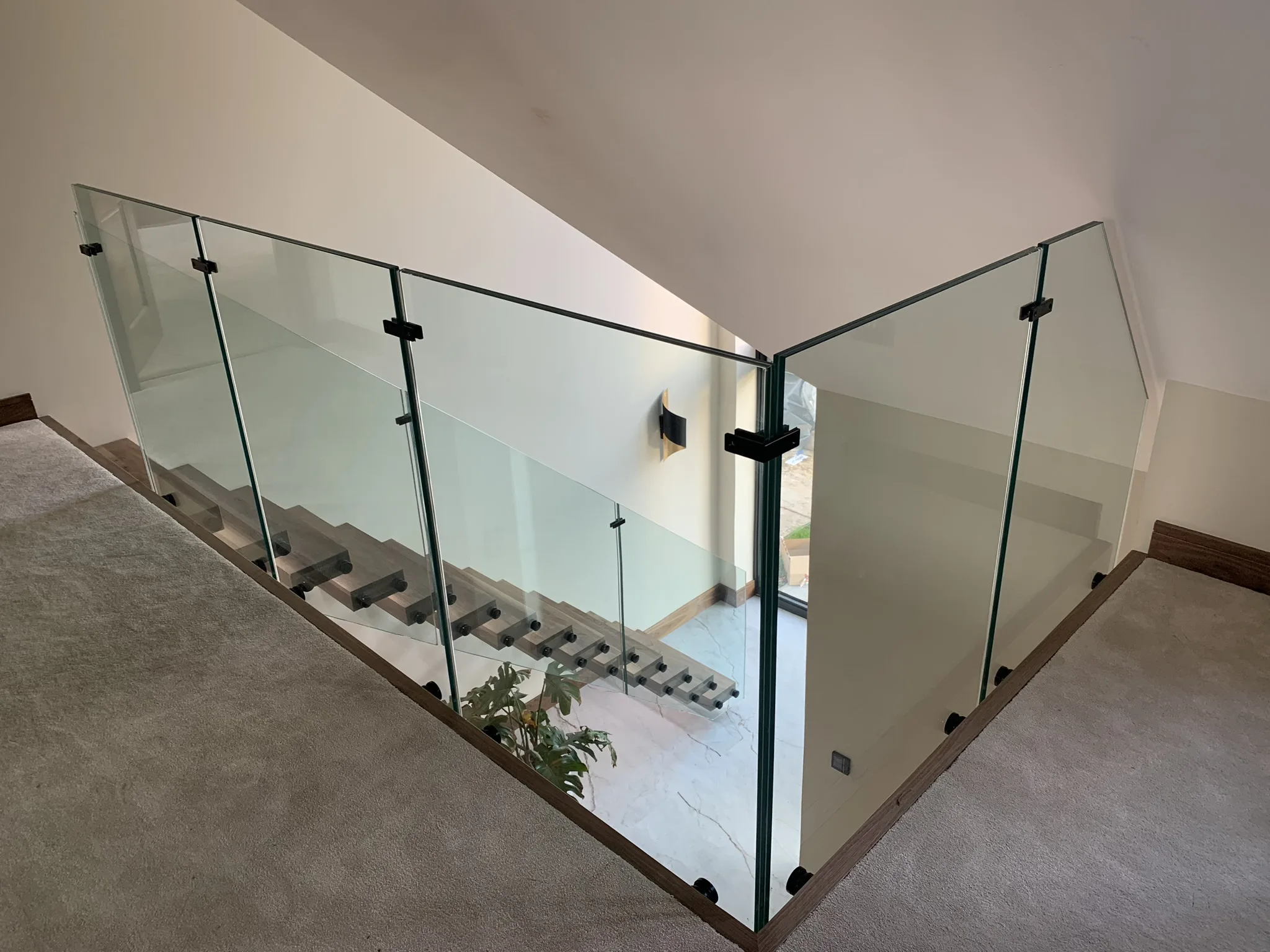 Side-mounted glass balustrade with black fixings on floating stairs