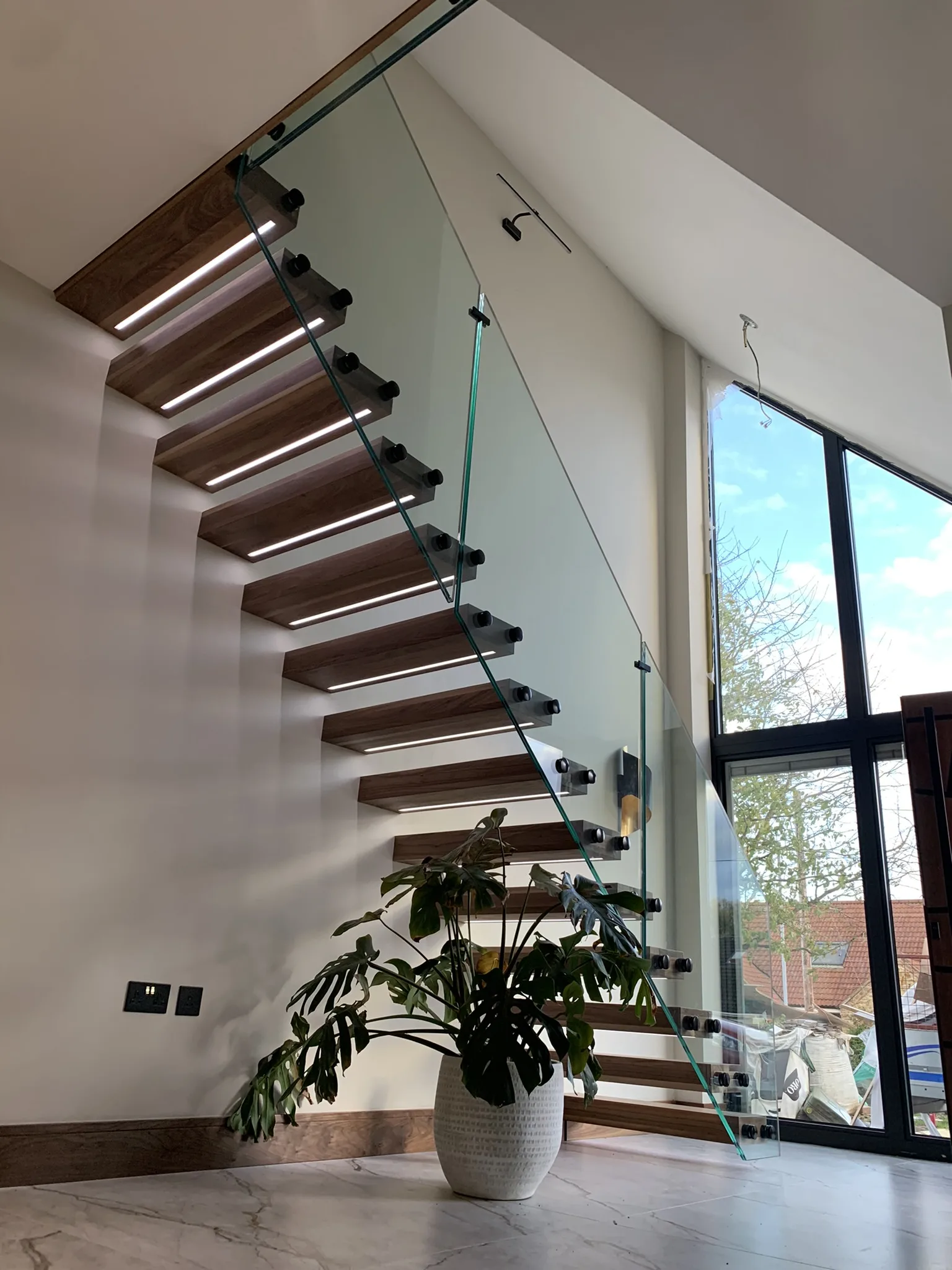 Walnut floating staircase with black standoffs and frameless glass