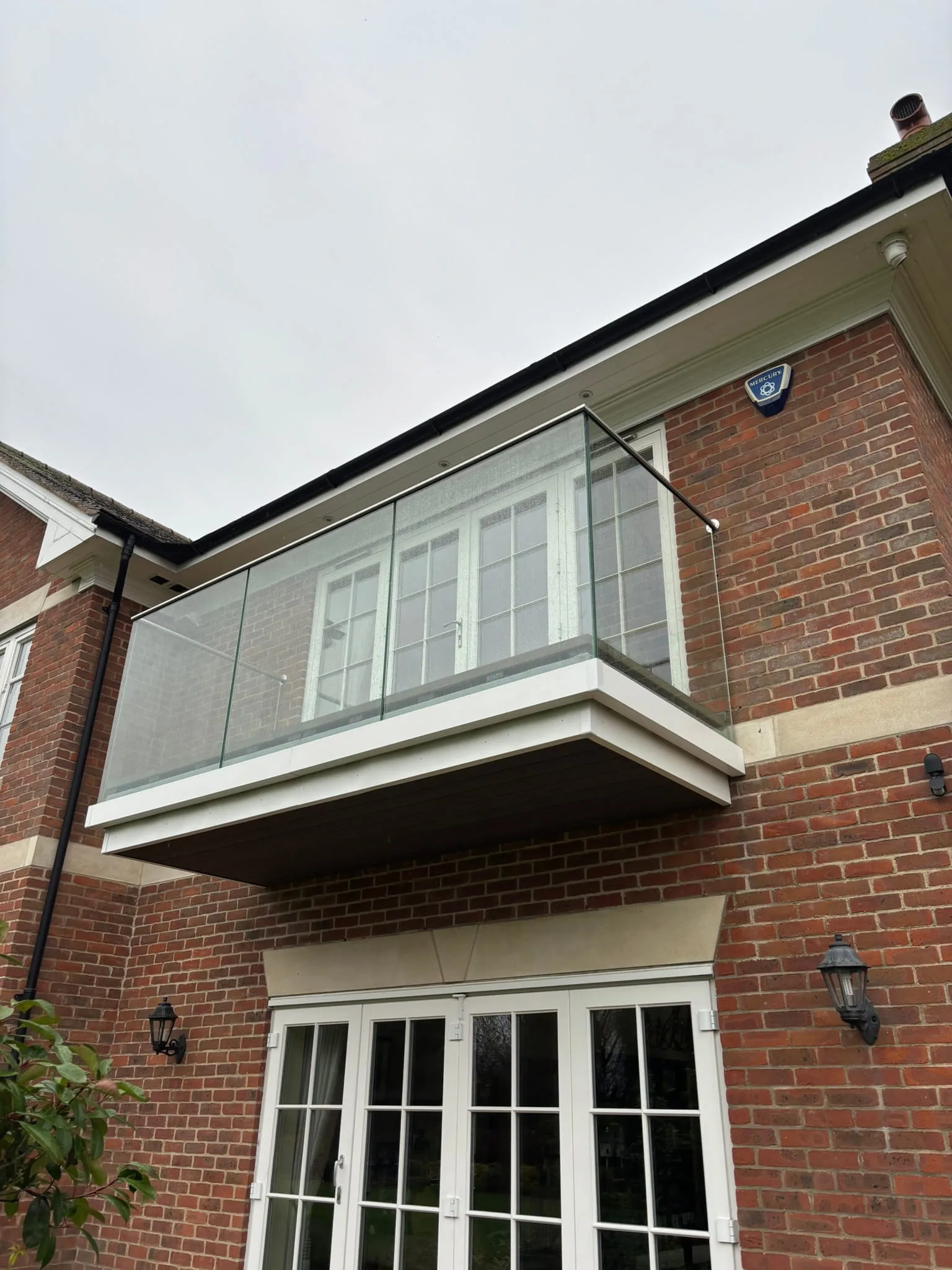 Brushed stainless steel handrail on frameless glass balustrade, Nottingham balcony renovation.