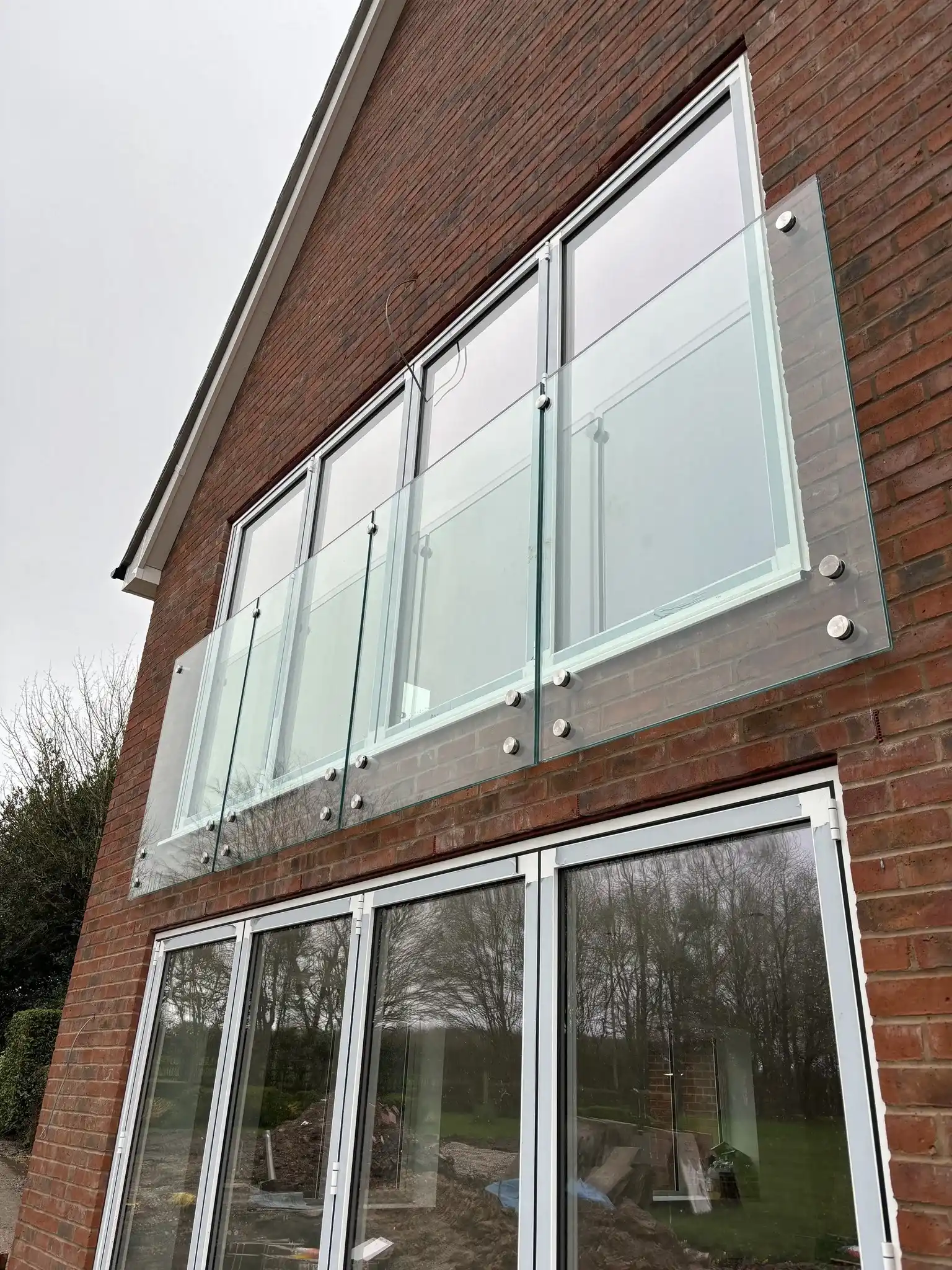 Frameless glass Juliet balcony on new-build brick property, Chesterfield, with stainless fixings.