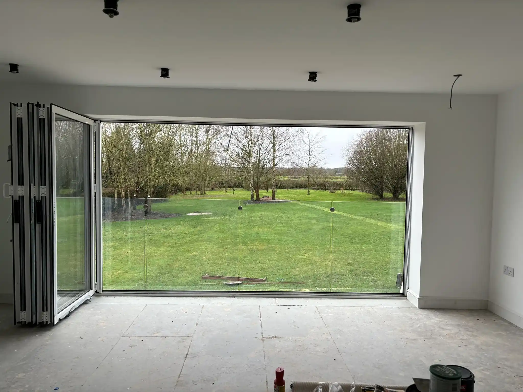 Interior view through bifold doors to garden with frameless glass Juliet balcony, Chesterfield.