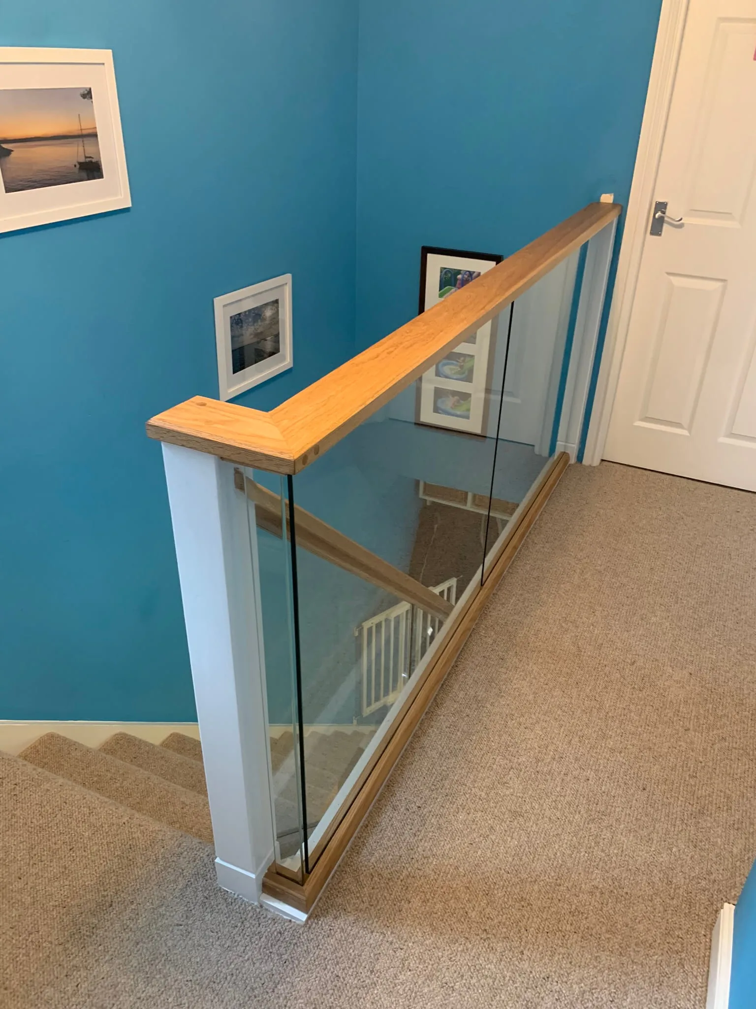 Landing view of glass staircase renovation showing oak handrail and toughened glass panels, Derby