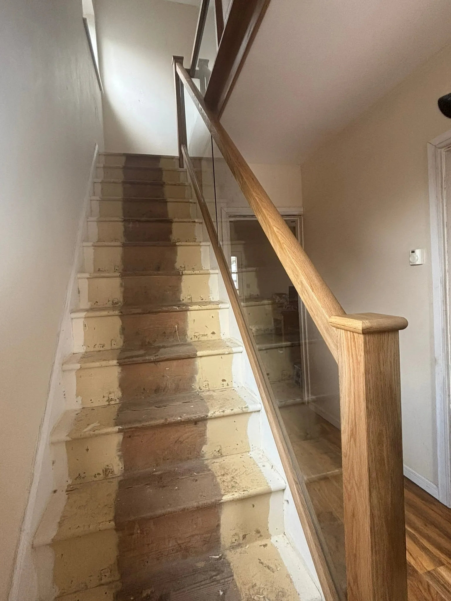 Modern oak staircase with clear glass replacing traditional spindles