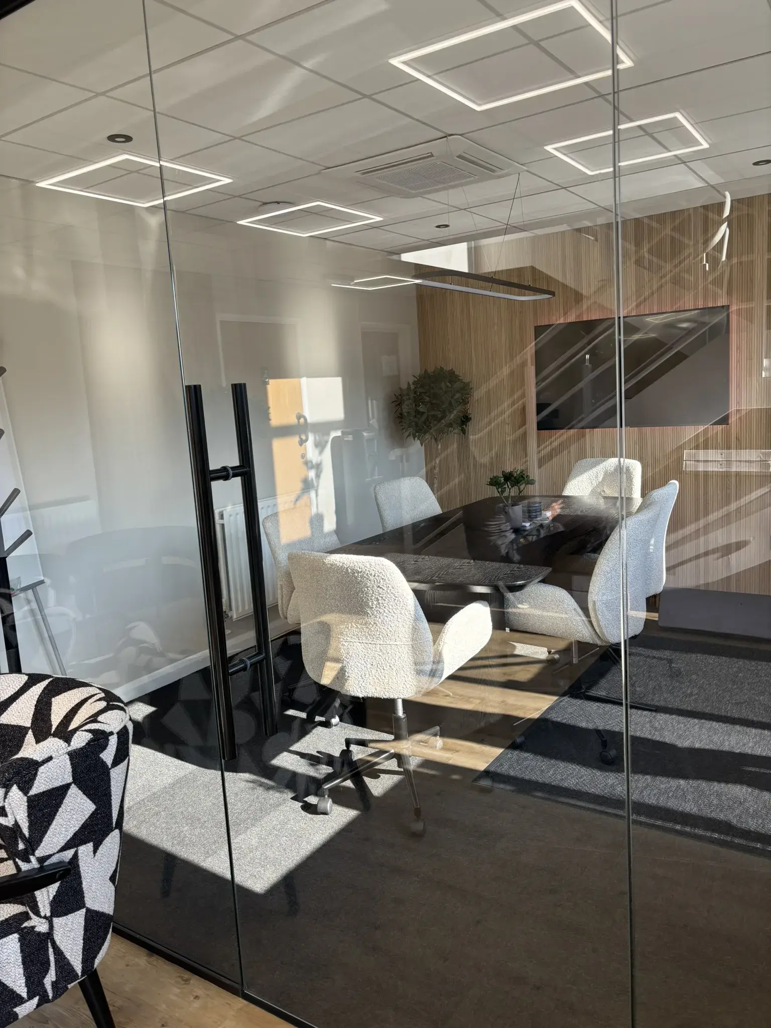 Frameless glass office partition with black aluminium frame installed in small meeting room