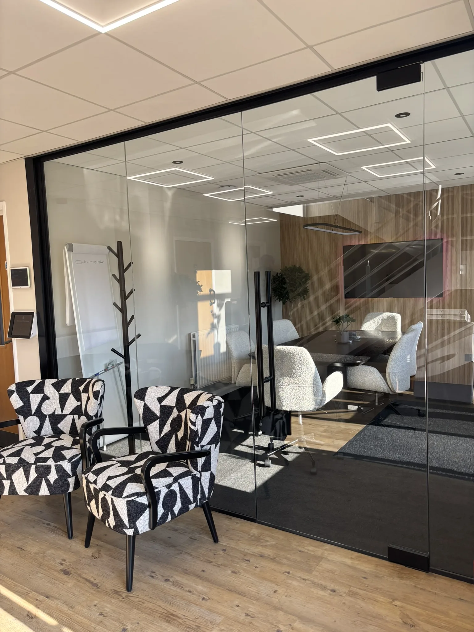 Frameless glass office partition with black aluminium frame installed in small meeting room