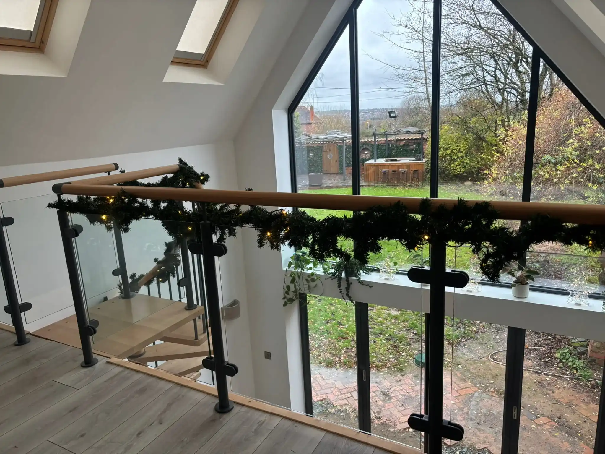 Bespoke basalt grey steel spiral staircase with beech treads and glass balustrades, Bingham